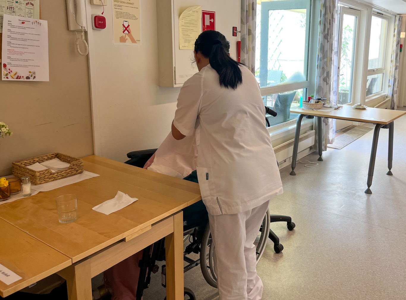 Helsefagarbeider med ryggen til som mater beboer