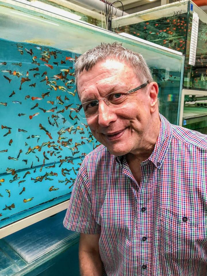 Svein Foss&aring; foran et karantene-akvarium. Han smiler til kameraet, og man ser sm&aring; fisker 
