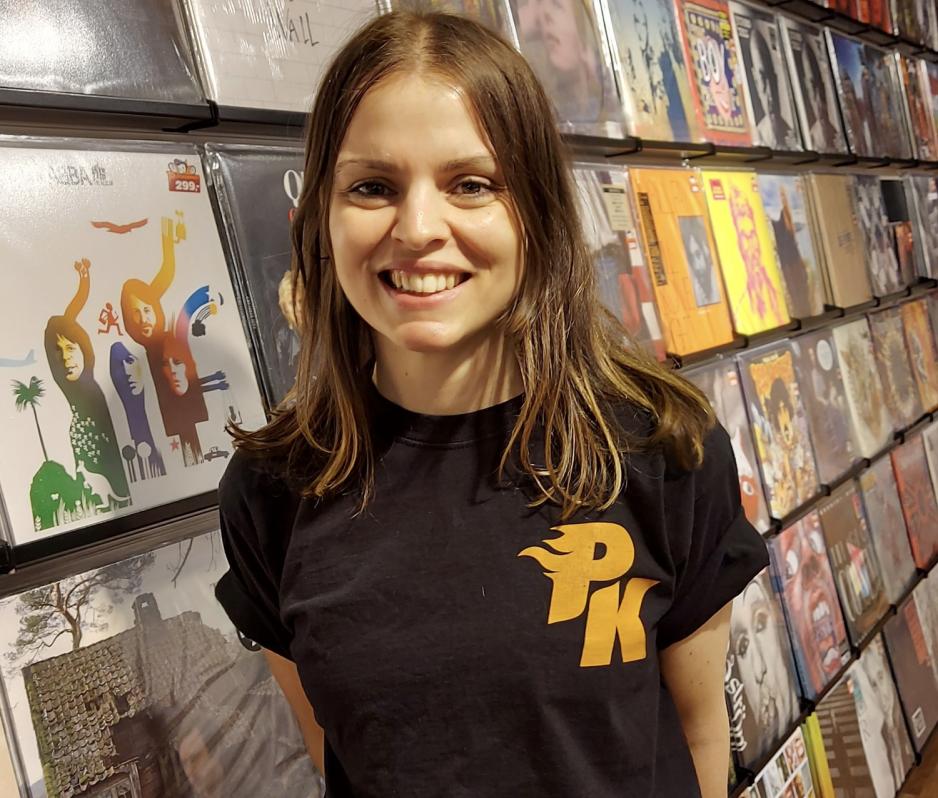 Butikksjef p&aring; platekompaniet foran vinylplater i butikken.