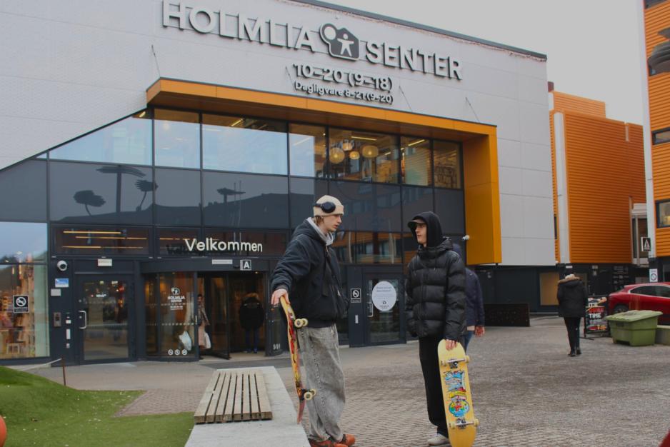 To gutter med skateboard, st&aring;r og snakker utenfor inngangen til Holmlia senter.