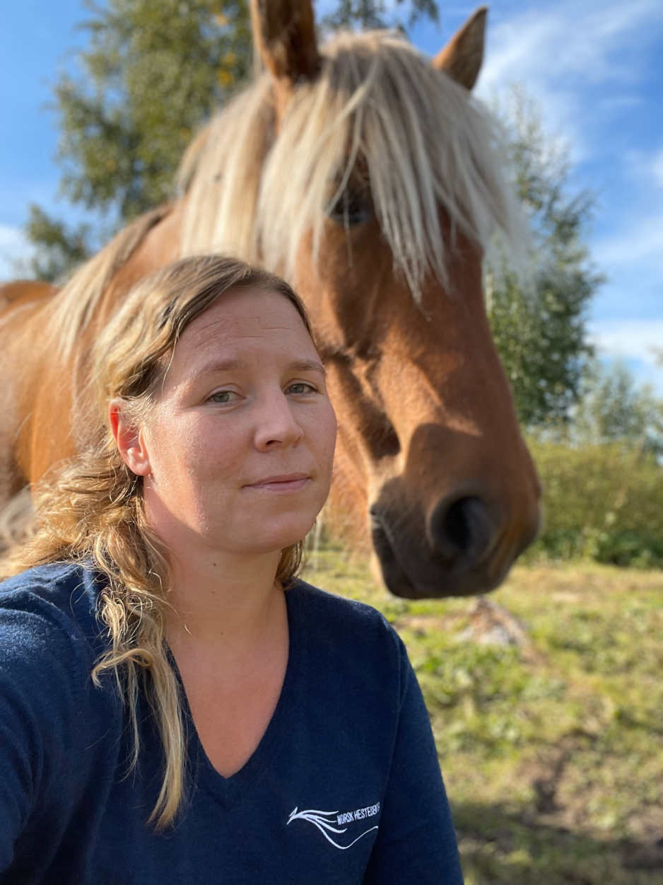 Blond kvinne sitter foran en brun hest p&aring; et jorde