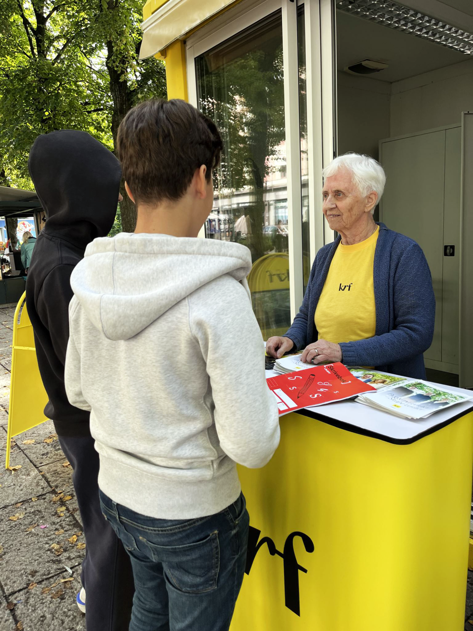 Dame som st&aring;r p&aring; stand for krf og snakker med to gutter om politikken deres
