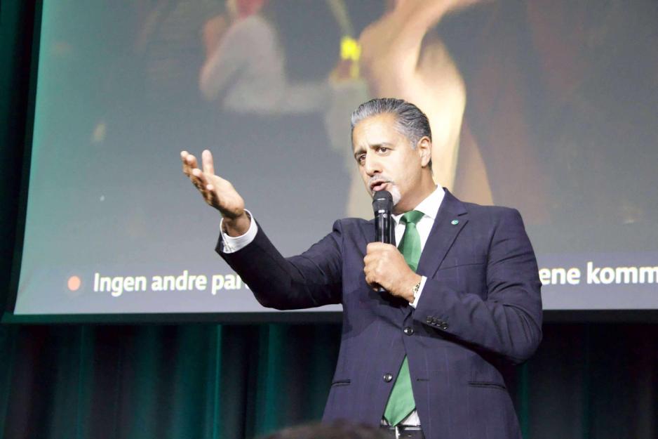 En mann i dress p&aring; scenen taler til publikum