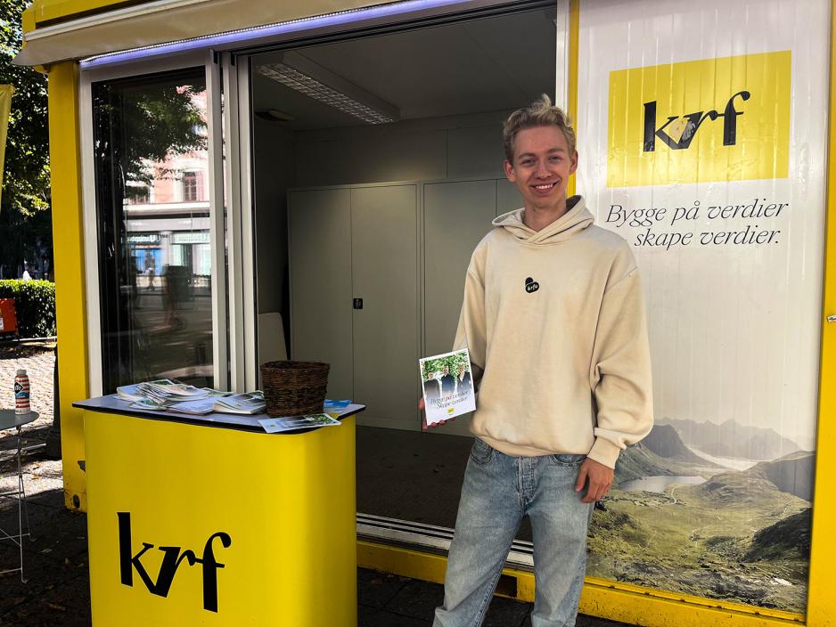 Gutt som st&aring;r foran KrF stand med partiprogram i h&aring;nden