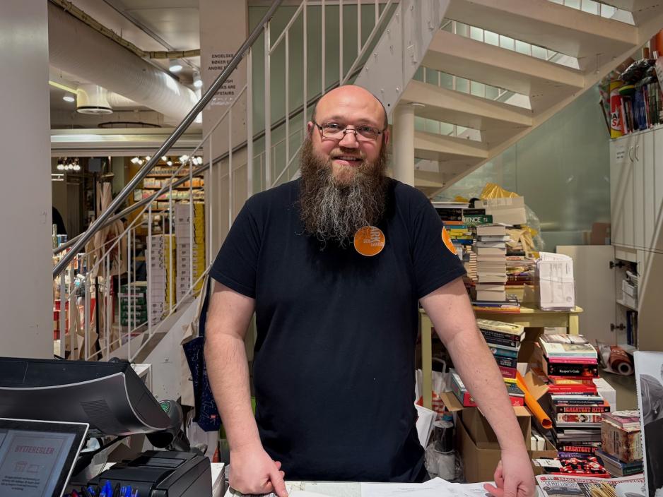 Butikkmedarbeider Christian Espeland st&aring;r bak kassa p&aring; Ark