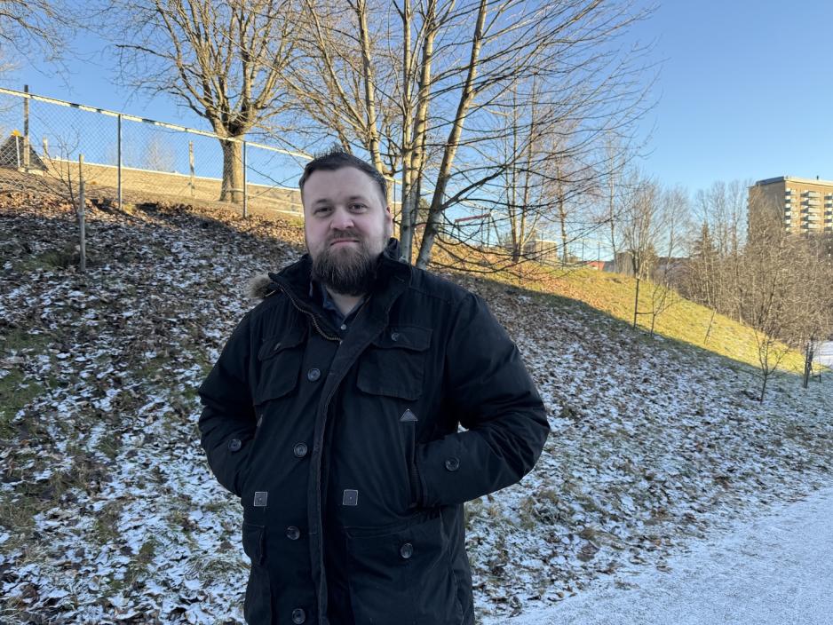 Mann i svart kåpe i en park