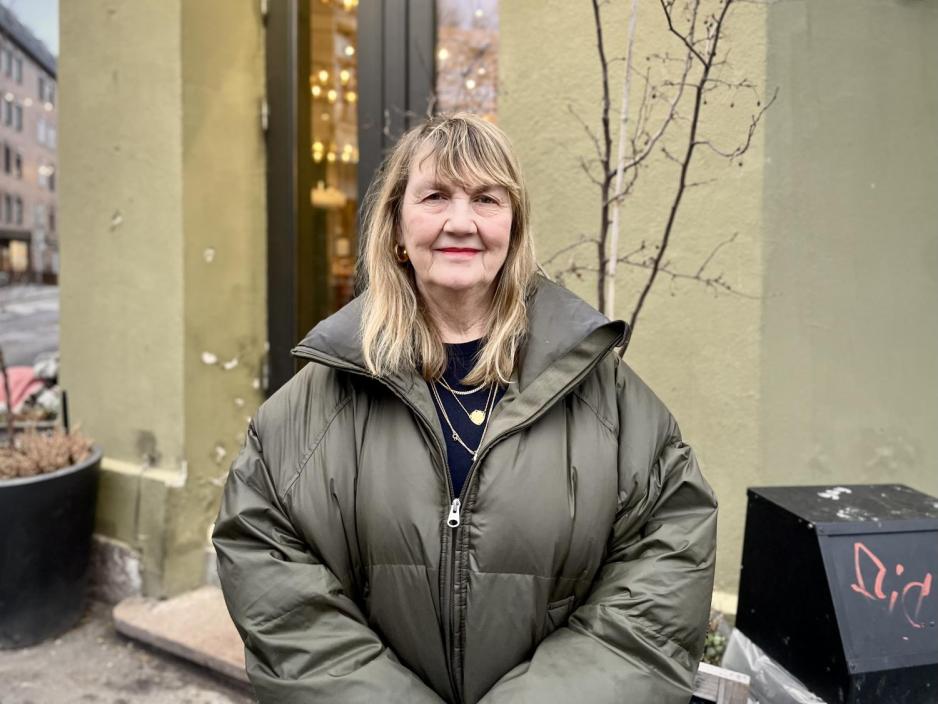 Dame st&aring;r foran en gr&oslash;nn vegg.