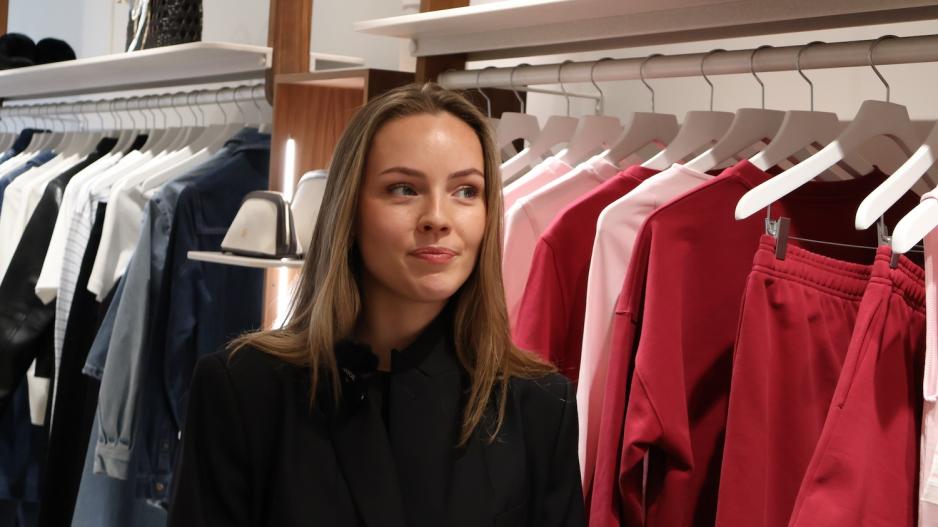 Ansatt på Camillia Phil står foran en rekke rosa plagg.