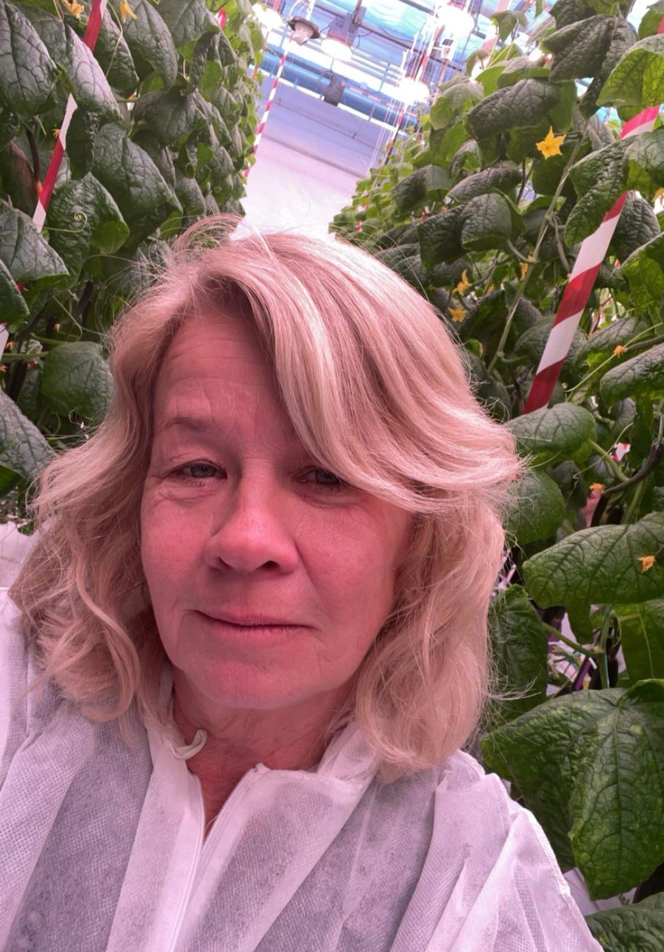 Sissel Torre står i et veksthus med masse planter.