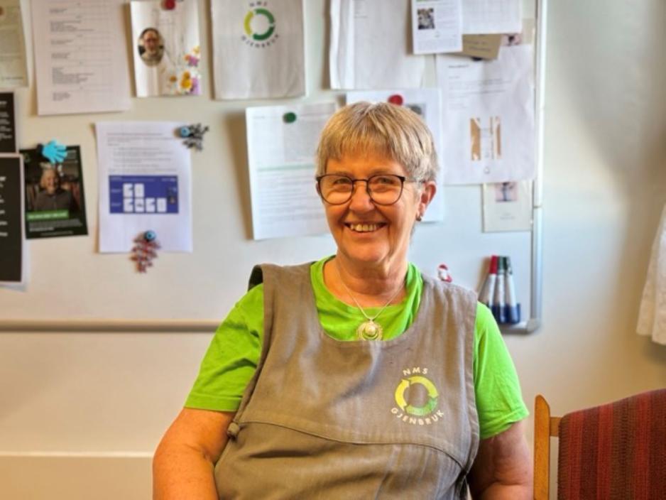 Irma Dagsloth Neef sitter på kontoret med et bredt smil og butikkens uniform.
