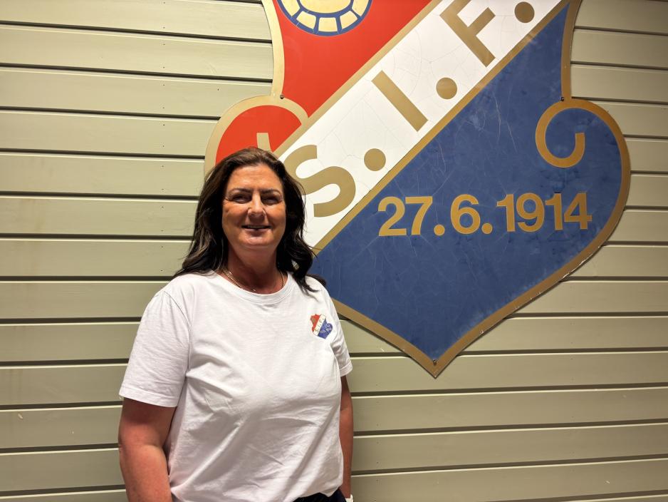 Kristin Auke Kværne, daglig leder i Slemmestad Idrettsforening, foran klubbens logo