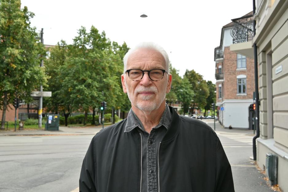 Frank Høifødt som poserer på gata foran bilvei, grønne trær og grå himmel.
