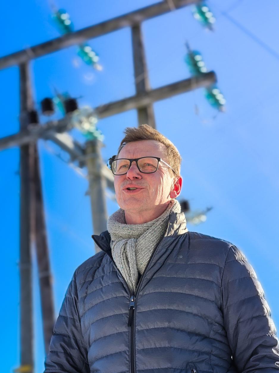 En mann st&aring;r ute i kaldv&aelig;ret foran en h&oslash;ytspennt ledning