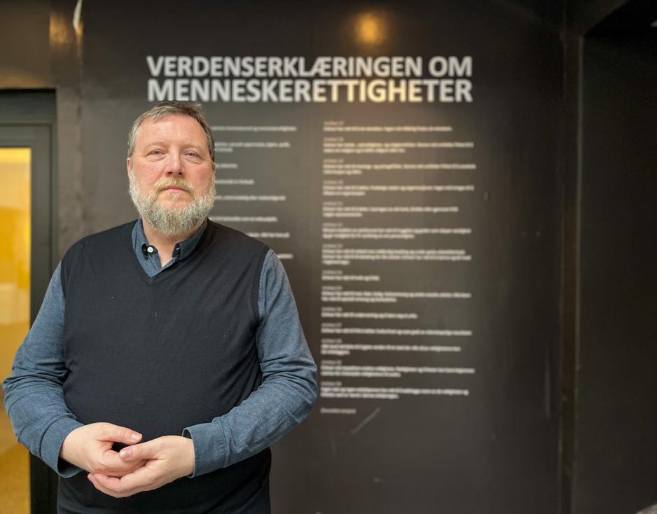 Bilde av politisk r&aring;dgiver. Bakgrunnen st&aring;r det menneskerettighetene.