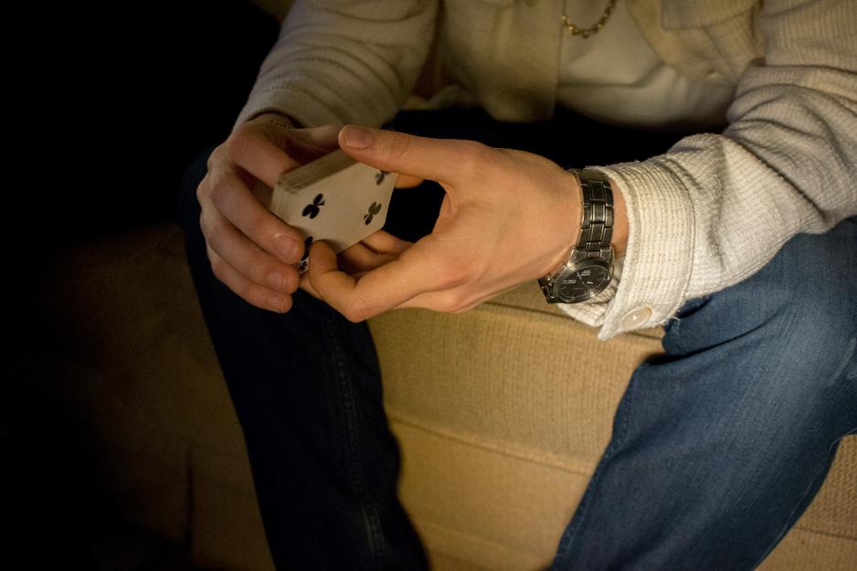 Artisten holder en kortstokk. P&aring; armen skinner en klokke.