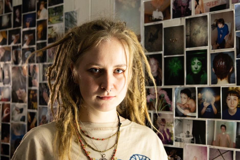 Mona Ulriche Schanche foran veggen sin med fotografier p&aring; utstillingen p&aring; Blodtusj&Kniven