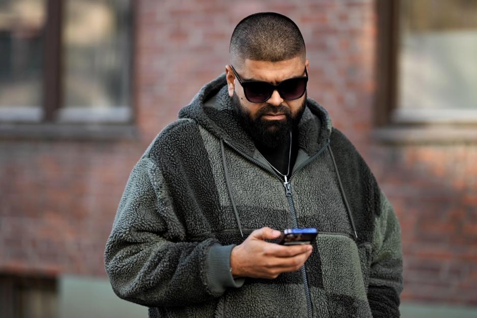 Mann med solbriller ser p&aring; telefonen sin