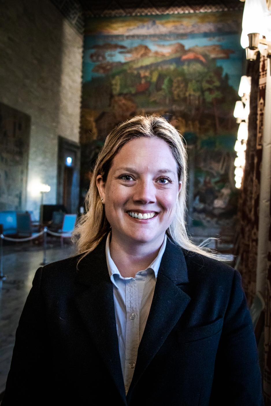 Pressebilde av Aina Stenersen. Dame med blondt, rett h&aring;r og svart dressjakke.