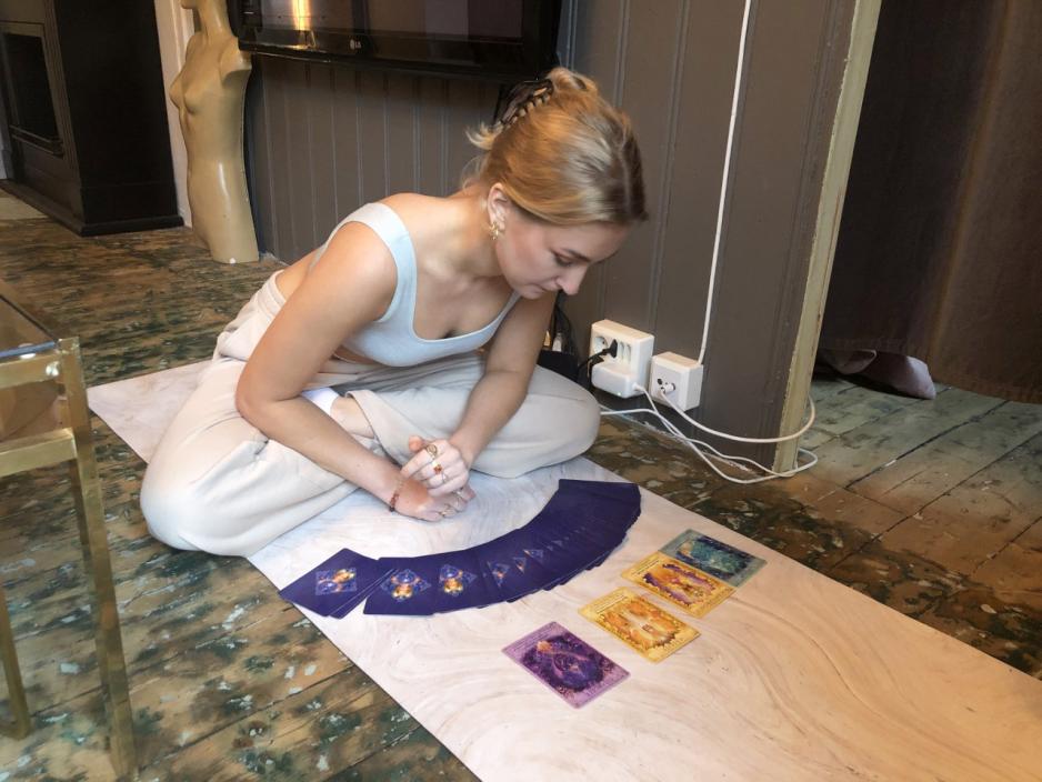Alma Skolmen sitter med beina i kors, og ser p&aring; fire selvutviklingskort som ligger p&aring; gulvet foran henne.