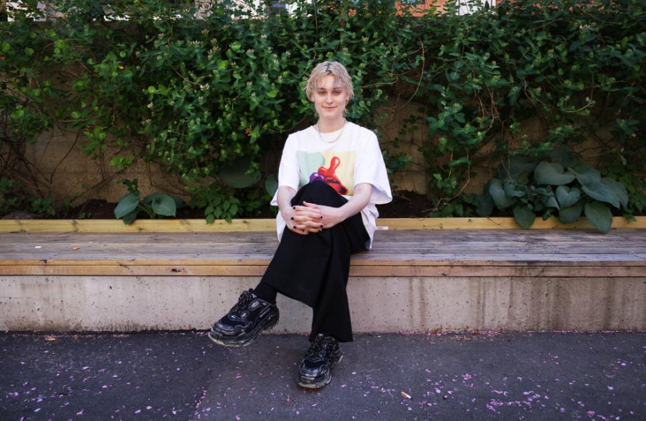 Portrett av Angelica Sophie Thorsen. Hun sitter p&aring; en benk med bena i kryss, og hendene foldet rundt kn&aelig;rne. 