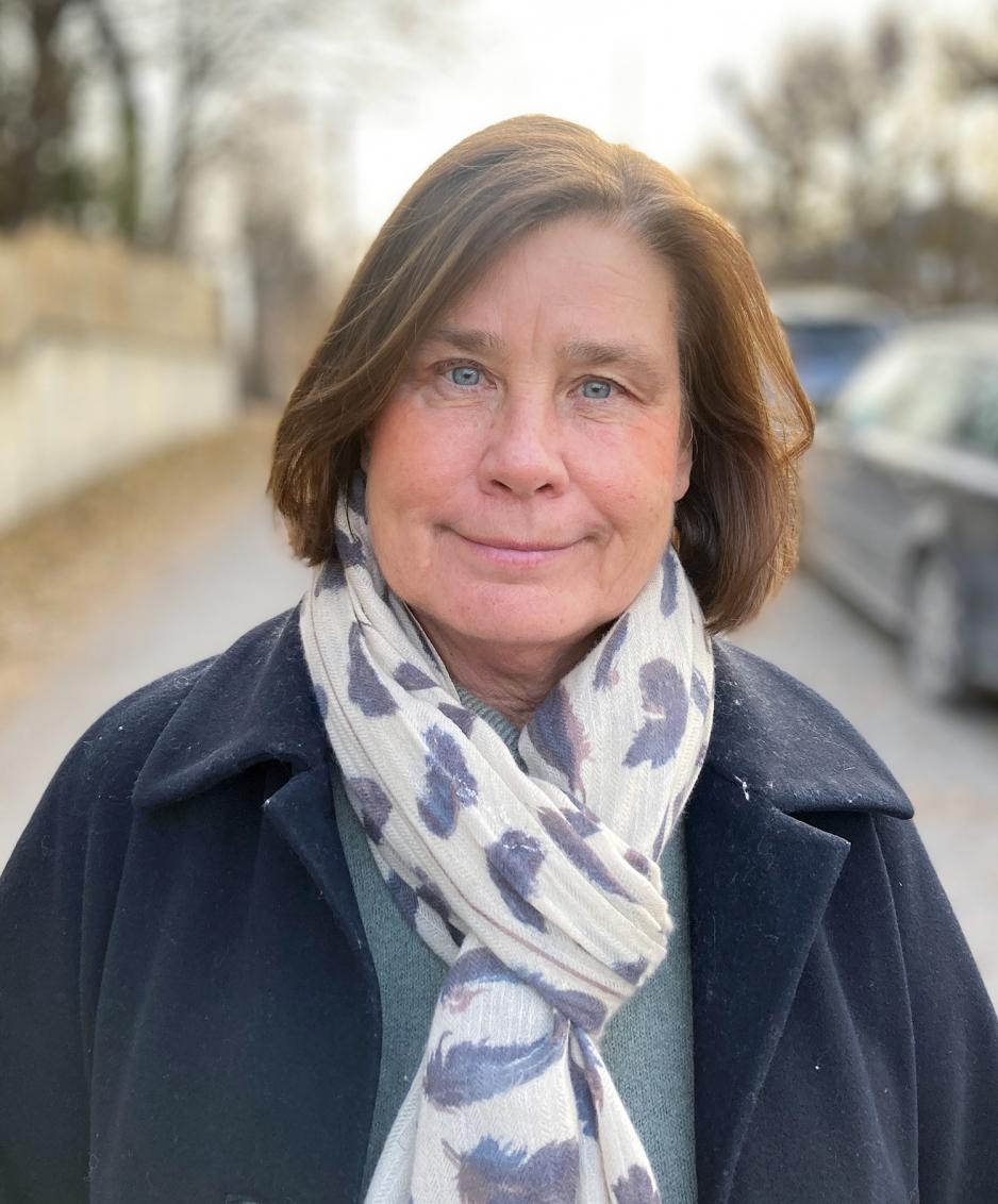 Dame med kort brunt h&aring;r, skjerf og svart jakke. 