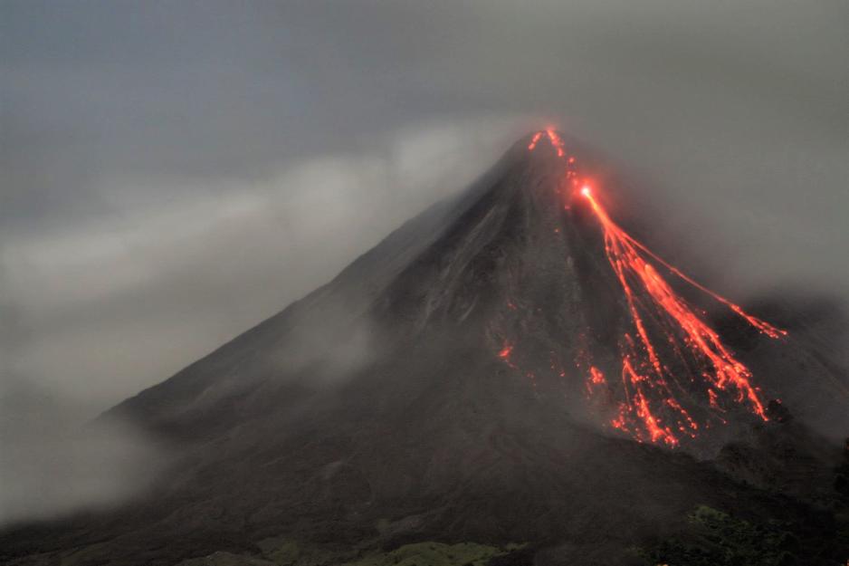 Den aktive vulkanen Arenal i Costa Rica. Lava flommer nedover fjellsidene, mens r&oslash;yken stiger til v&aelig;rs.