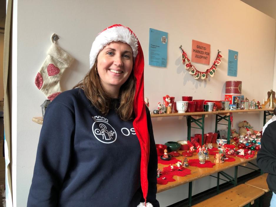 Astrid st&aring;r smilende foran et bord med julepynt. Hun har p&aring; en r&oslash;d nisselue.