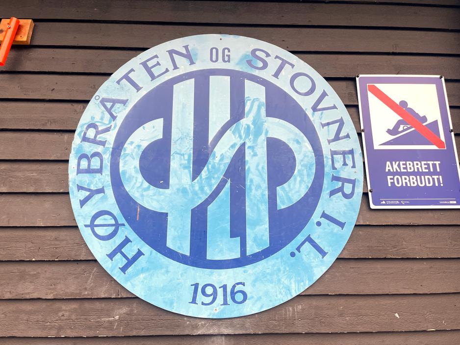 et bl&aring;tt skilt hengende p&aring; BUA Stovner hvor det st&aring;r H&oslash;ybr&aring;ten og Stovner idrettslag