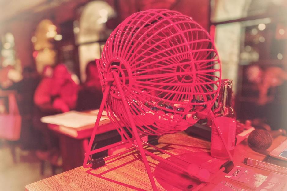 Her ser vi en bingo maskin som st&aring;r p&aring; et bord. Det r&oslash;de lyset reflekterer over den. 