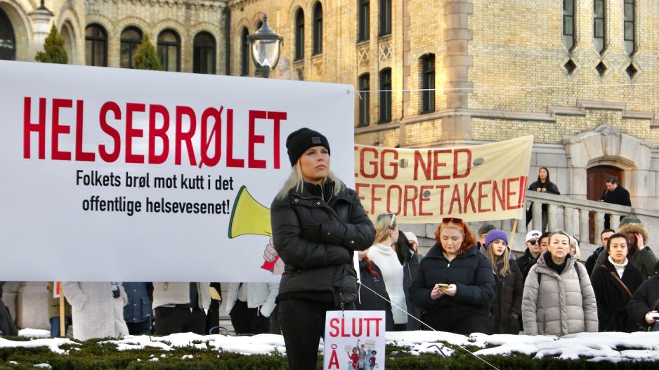 kvinne st&aring;r foran et skilt med helsebr&oslash;let skrevet p&aring; 