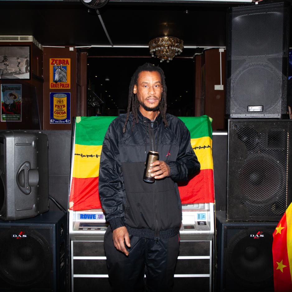 Jason Saunders fotografert foran h&oslash;yttalerne. Han eier en svart drakt og holder en &oslash;l.