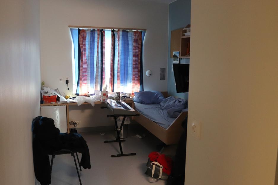 Et lite rom med gardinene trukket for. Foran vinduet er et bord som er rotete. En seng st&aring;r ved siden av bordet og foran den er det er keyboard- piano.