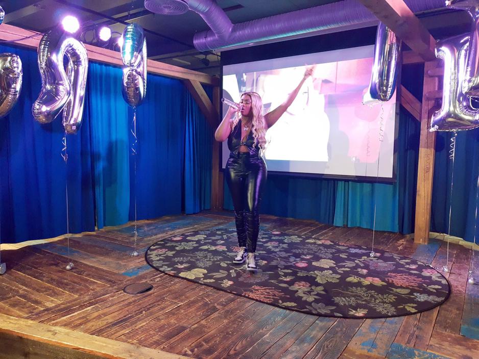 Rapper Cherie Mwangi st&aring;r p&aring; en scene med h&aring;nda i v&aelig;ret.