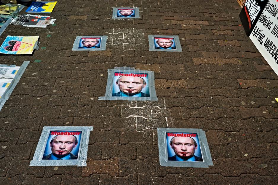 Plakater av Vladimir Putin med blod ut av munnen. Plakatene er p&aring; bakken utenfor ambassaden i Frankfurt.