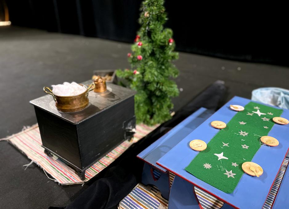 Bildet viser et dekt bord og en liten gr&oslash;tkjele klar til Nissemor under forestilling. Bordet er bl&aring;tt med gr&oslash;nn duk og er dekt p&aring; med tre-servise. 