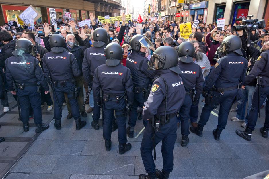 Politet st&aring;r foran en demonstrerende folkemengde i Spania