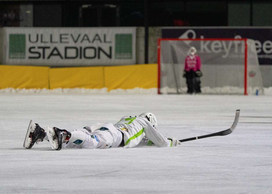 Bandyspiller ligger p&aring; isen