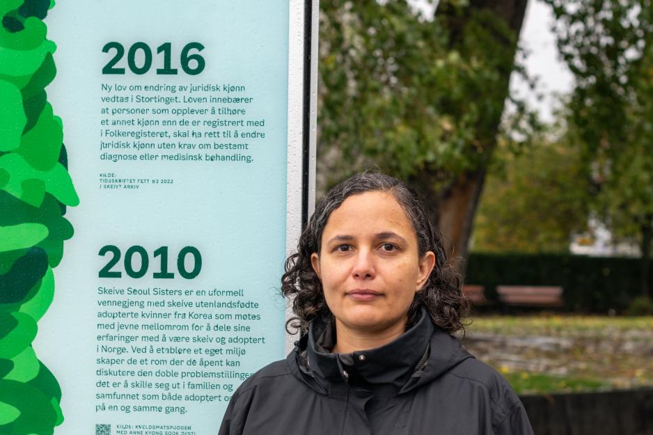 Kvinne st&aring;r foran utstilling hun har laget