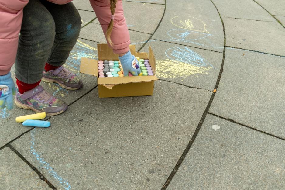 En jente tegner med kritt p&aring; bakken