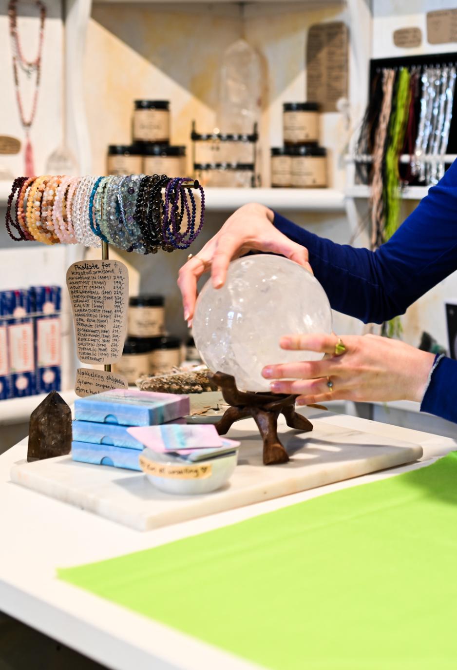 En rosa kule i rosenkvarts blir plassert p&aring; disken i butikken.