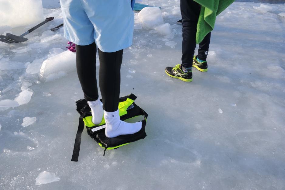 En elev st&aring;r p&aring; en redningsvest f&oslash;r isbadingen. 