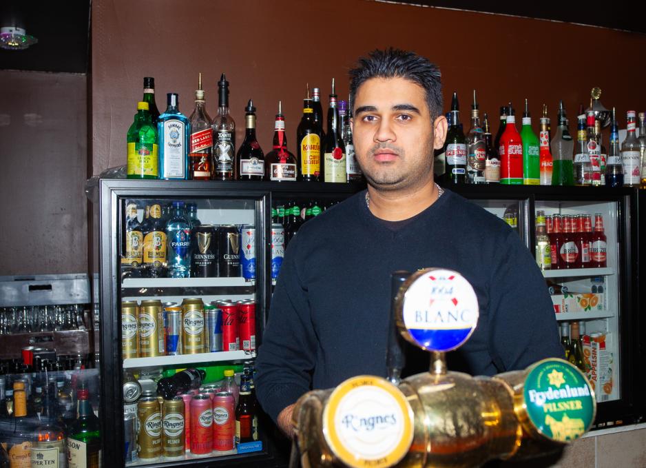 Rashid Muhammed fotografert i baren. Bak han finnes flasker og i forgrunnen kan man se &oslash;ltapper.