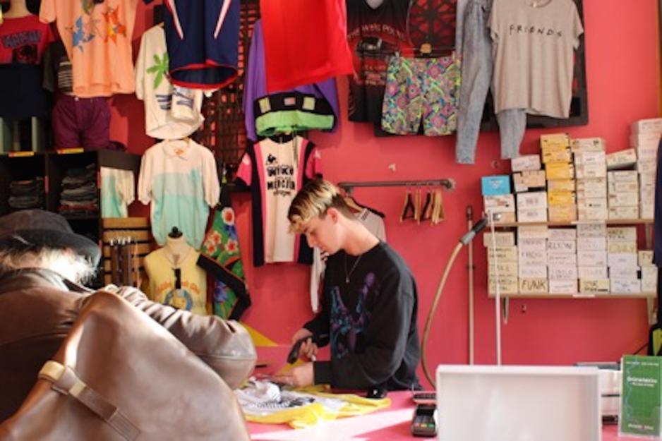 Phillip Eskildsen st&aring;r i kassen og ekspederer en kunde. 