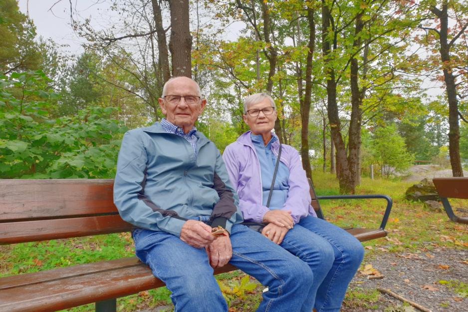 Et eldre ektepar sitter p&aring; en benk ute i en gr&oslash;nn park.