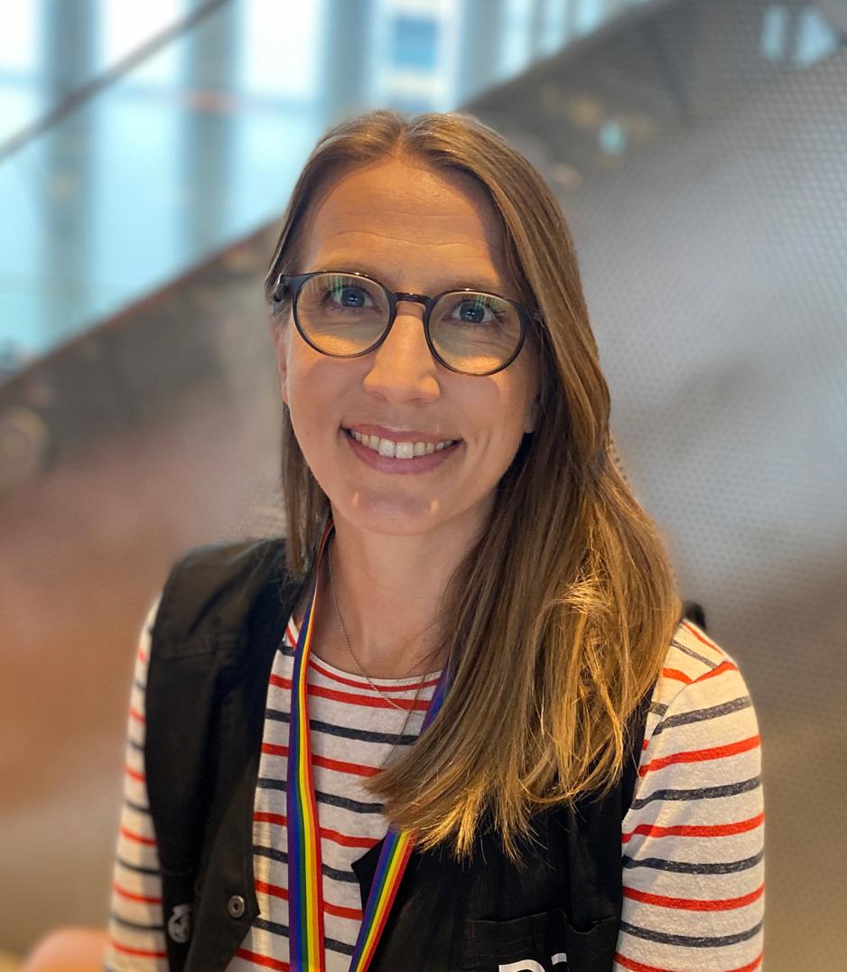 Portrett av Eldrid Holje Stjernvang. Hun har m&oslash;rk blondt h&aring;r og briller, og en stripete t-skjorte med en m&oslash;rk vest over.