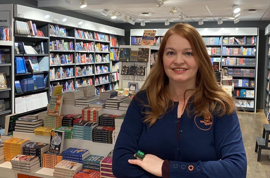 Elin Urke st&aring;r foran bokhyller inne i butikken. 