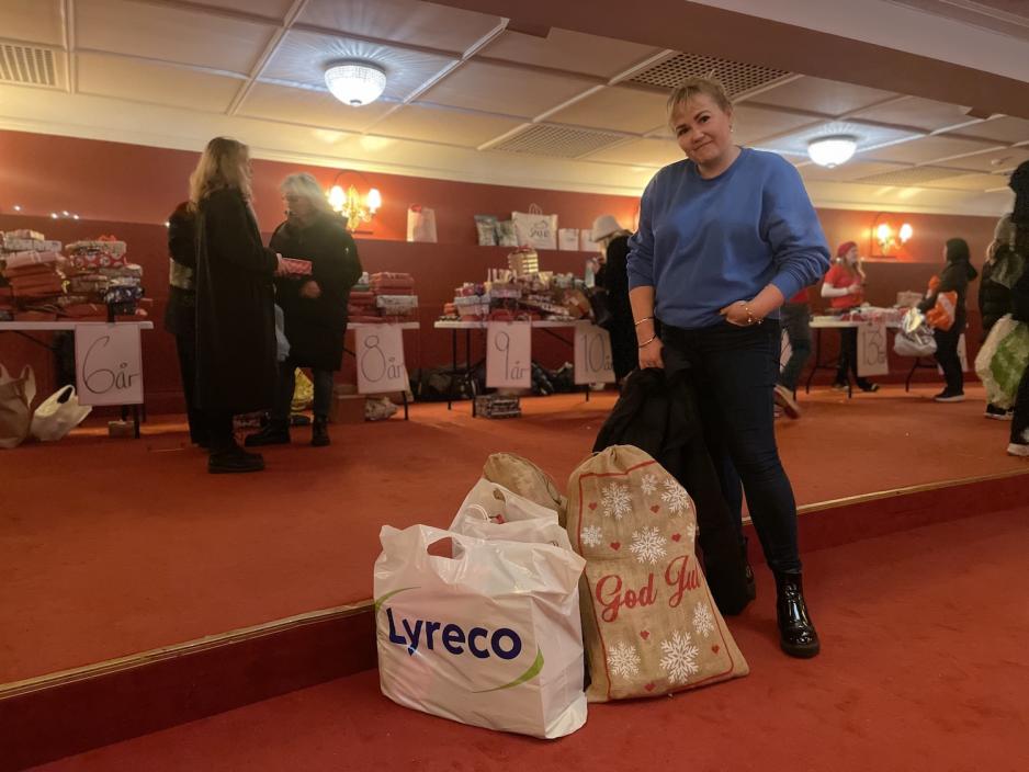 Dame som st&aring;r p&aring; Hotel Christiania Teater med julegaver til God jul, lille venn