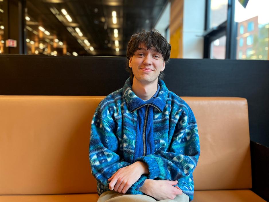 Erlend Sneve, l&aelig;rerstudent ved OsloMet, sitter smilende i en av sofagruppene i studenthallen i P52