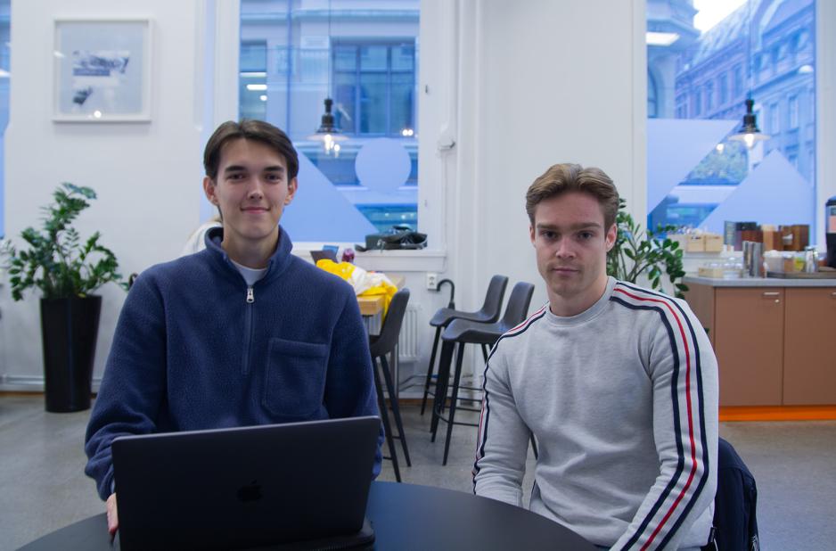 En m&oslash;rkh&aring;ret gutt sitter med bl&aring; genser og en svart PC foran seg. En annen gutt sitter til h&oslash;yre for han, han har lyse brunt h&aring;r. 