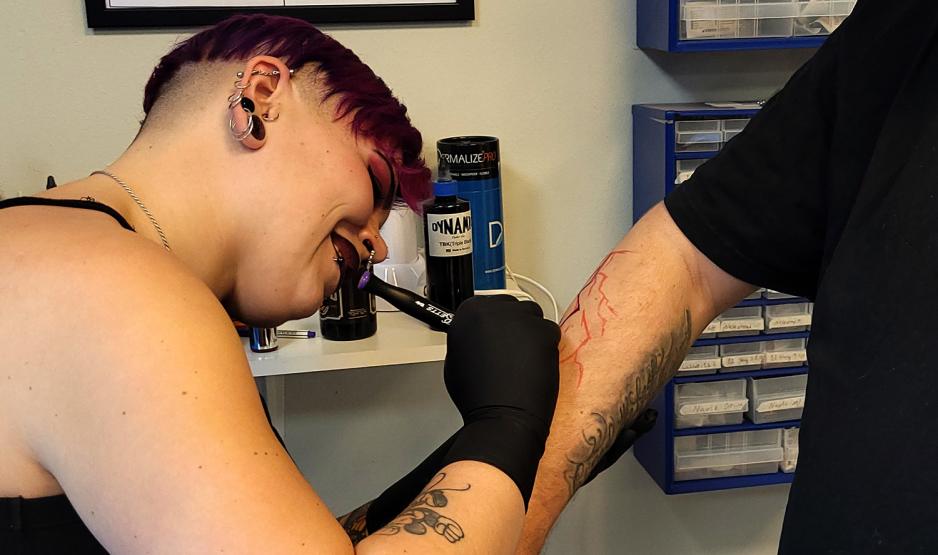 Tatov&oslash;r som teiknar p&aring; armen til ein kunde, f&oslash;r ho startar &aring; tatovere.